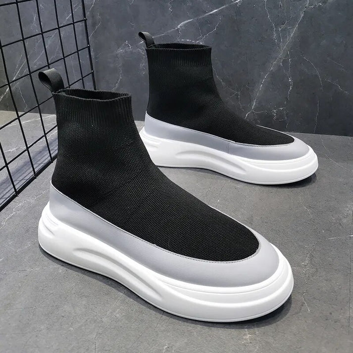 Scarpe da ginnastica nere e bianche su sfondo grigio, design moderno con suola spessa, stile calzino, moda urbana, calzature sportive eleganti.