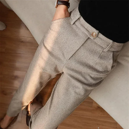 Pantaloni eleganti da donna in tessuto grigio chiaro, stile formale, con tasche laterali e cintura, indossati con maglia nera.