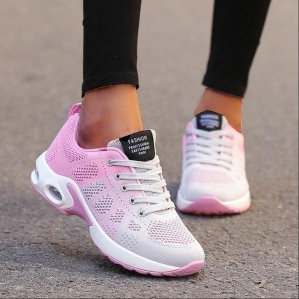 Scarpe da ginnastica rosa e bianche su strada asfaltata, design traspirante, suola ammortizzata, ideali per corsa e fitness. Scarpe sportive donna.