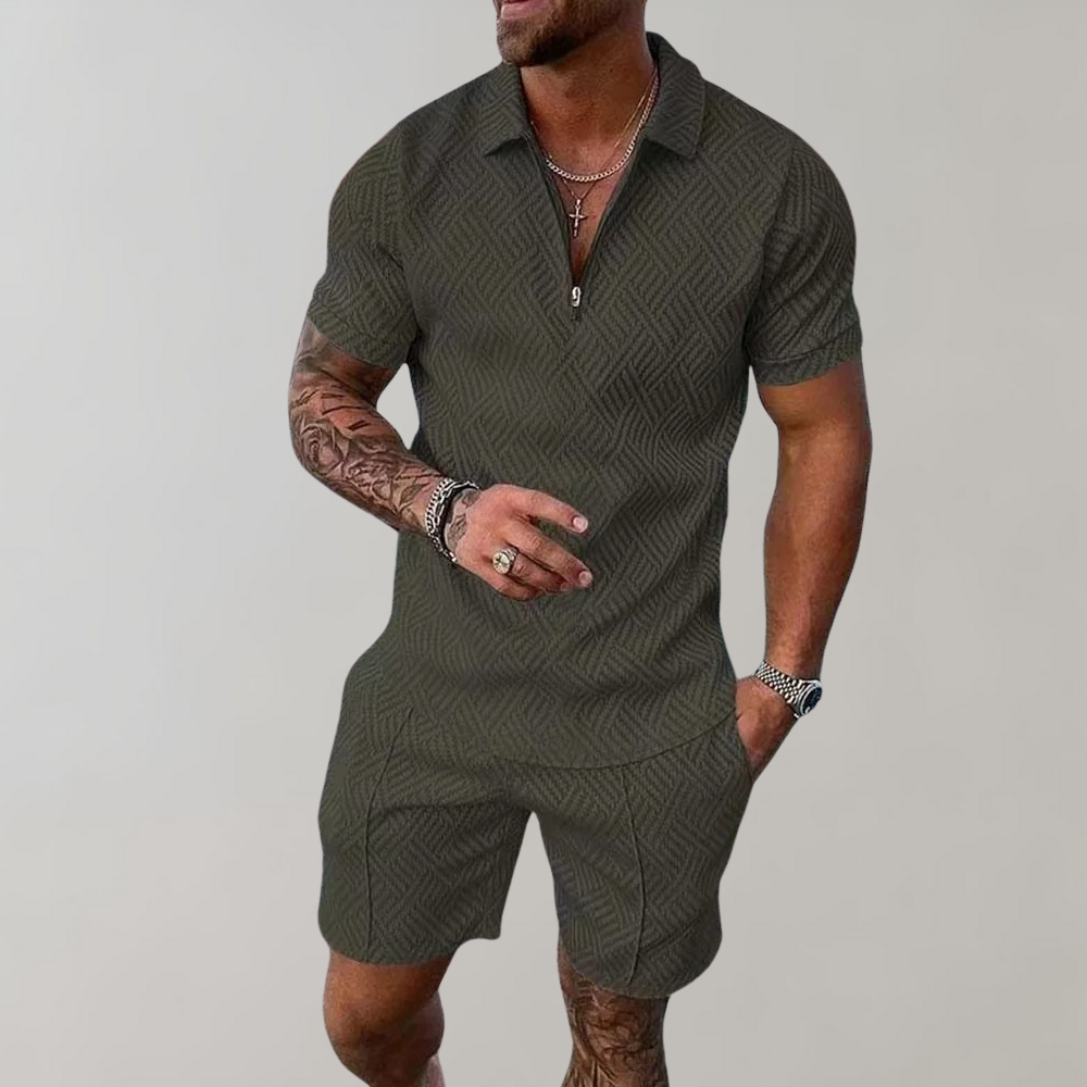 Uomo con tuta estiva verde oliva, motivo geometrico, maniche corte, collana e bracciali. Stile casual elegante, moda maschile estiva.