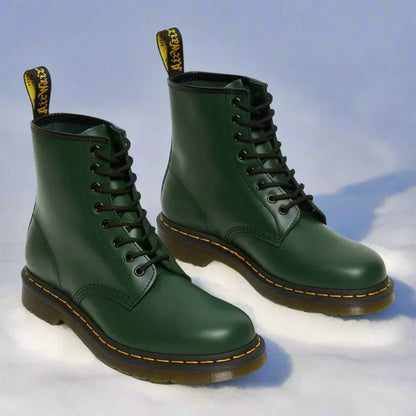 Stivali Dr. Martens verdi su neve, design classico con lacci neri e cuciture gialle, moda invernale, calzature iconiche.