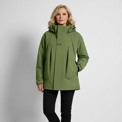 Donna in giacca verde impermeabile con cappuccio, design moderno, ideale per escursioni e attività outdoor. Abbigliamento tecnico, moda autunno-inverno.