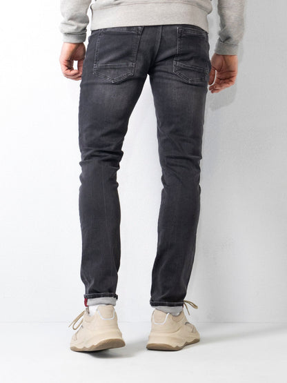 Jeans slim fit uomo, colore nero, indossati con sneakers bianche e felpa grigia. Moda casual maschile, abbigliamento moderno e confortevole.
