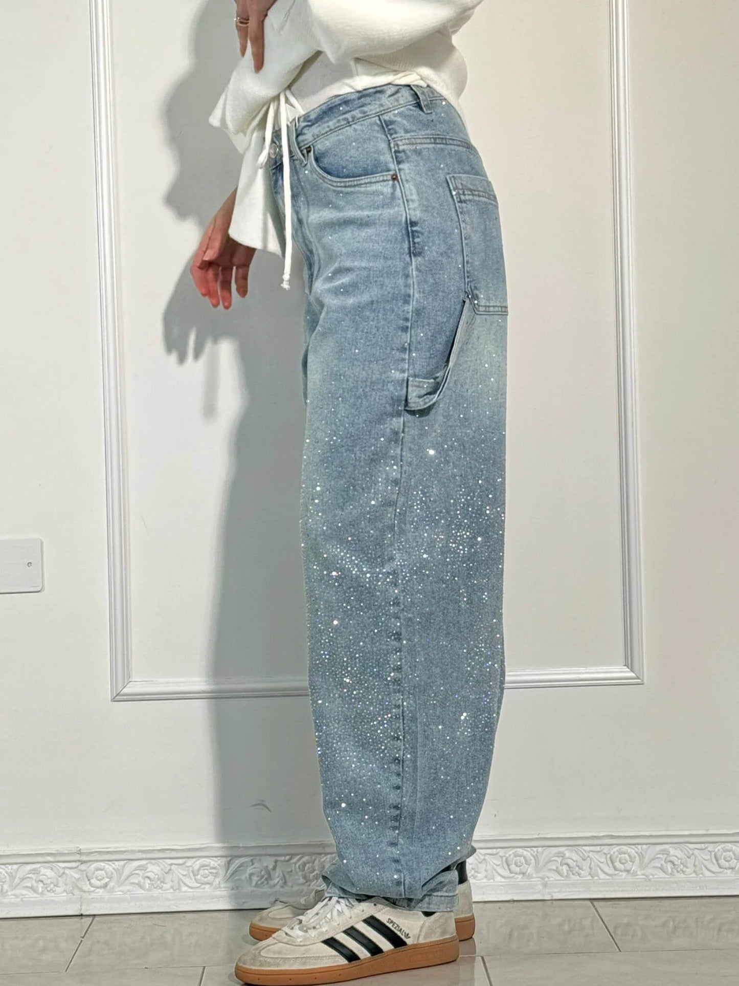 Jeans a vita alta con paillettes, tasca laterale, indossati da una persona in piedi. Moda casual, stile trendy, abbigliamento femminile.