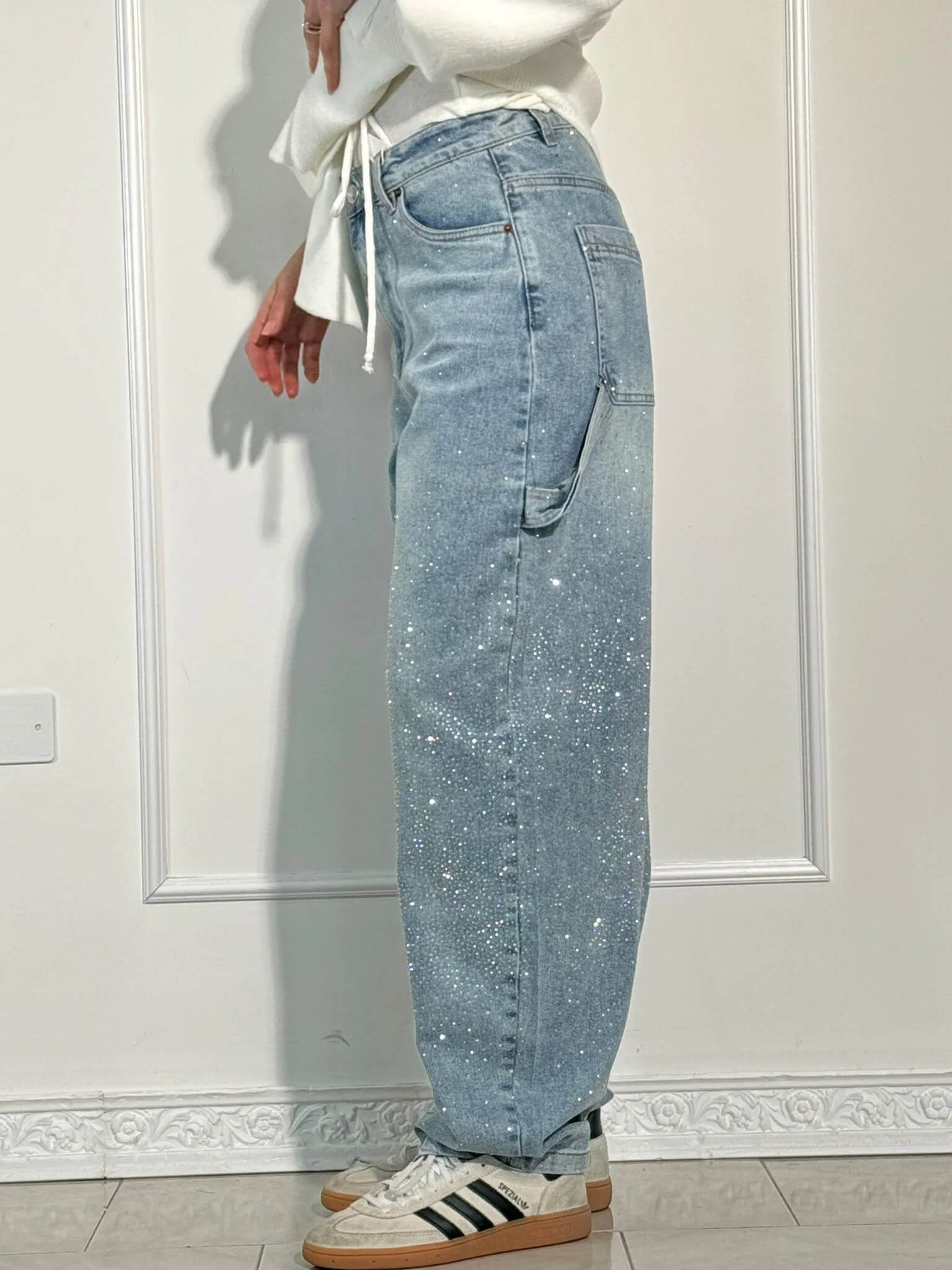 Jeans a vita alta con paillettes, tasca laterale, indossati da una persona in piedi. Moda casual, stile trendy, abbigliamento femminile.