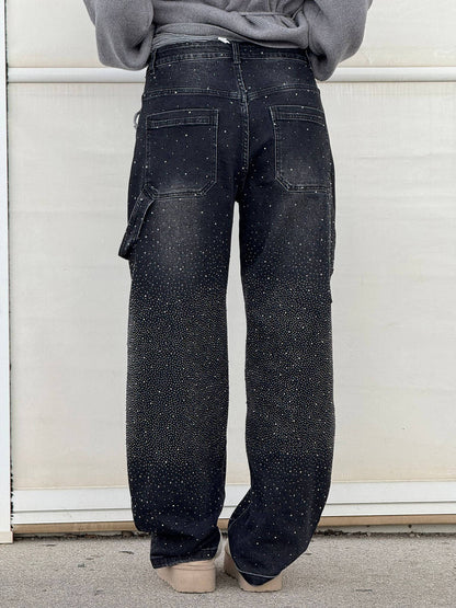 Jeans neri con strass, tasche posteriori, vestibilità ampia, indossati da una persona di spalle. Moda casual, stile urban chic.