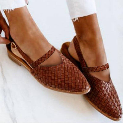 Scarpe intrecciate in pelle marrone, design elegante e casual, indossate con pantaloni bianchi. Scarpe estive alla moda, comode e traspiranti.
