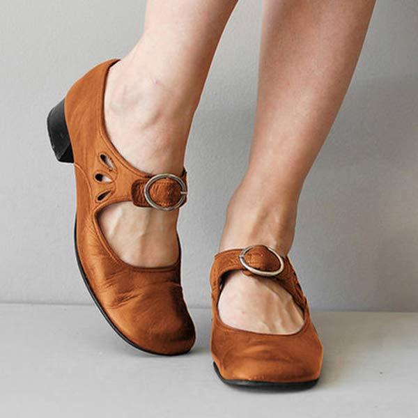 Scarpe Mary Jane in pelle marrone con tacco basso e cinturino con fibbia, indossate su pavimento grigio. Moda calzature donna eleganti e comode.