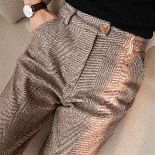 Pantaloni eleganti in tessuto a spina di pesce marrone chiaro, chiusura con bottone, indossati con maglia nera. Stile classico e sofisticato.