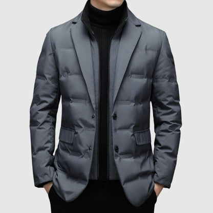 Giacca invernale uomo grigia elegante, imbottita, con chiusura a bottoni, indossata sopra maglione nero. Moda maschile, abbigliamento caldo.