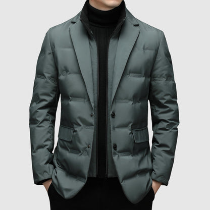 Giacca imbottita uomo elegante, colore grigio scuro, con bottoni e tasche, indossata sopra maglione nero. Moda invernale maschile.
