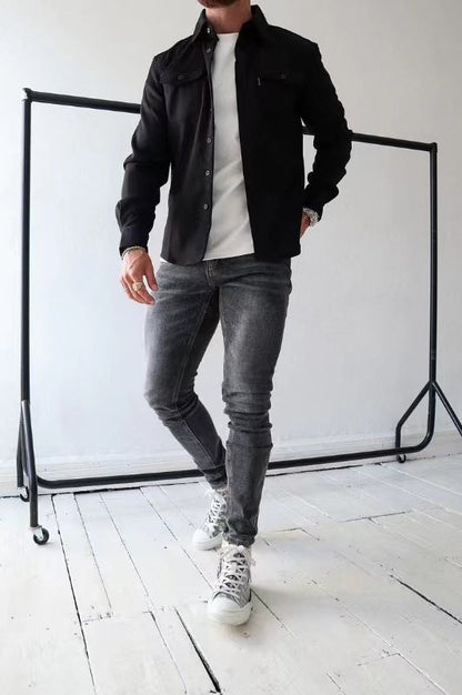 Uomo in jeans grigi e giacca nera su sfondo bianco, posa casual. Moda maschile, abbigliamento moderno, stile urbano.