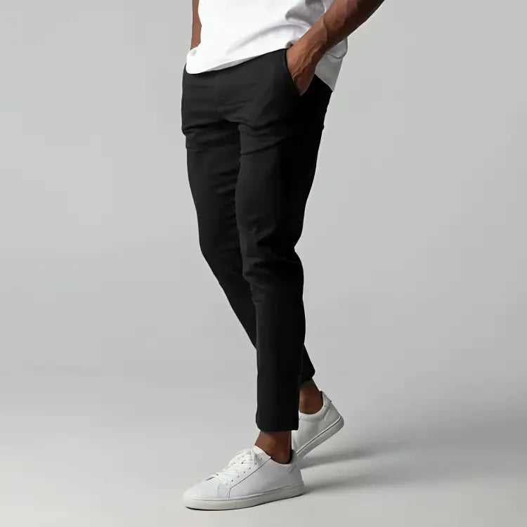 Pantaloni neri eleganti da uomo, abbinati a scarpe da ginnastica bianche e maglietta bianca. Stile casual moderno, moda maschile.