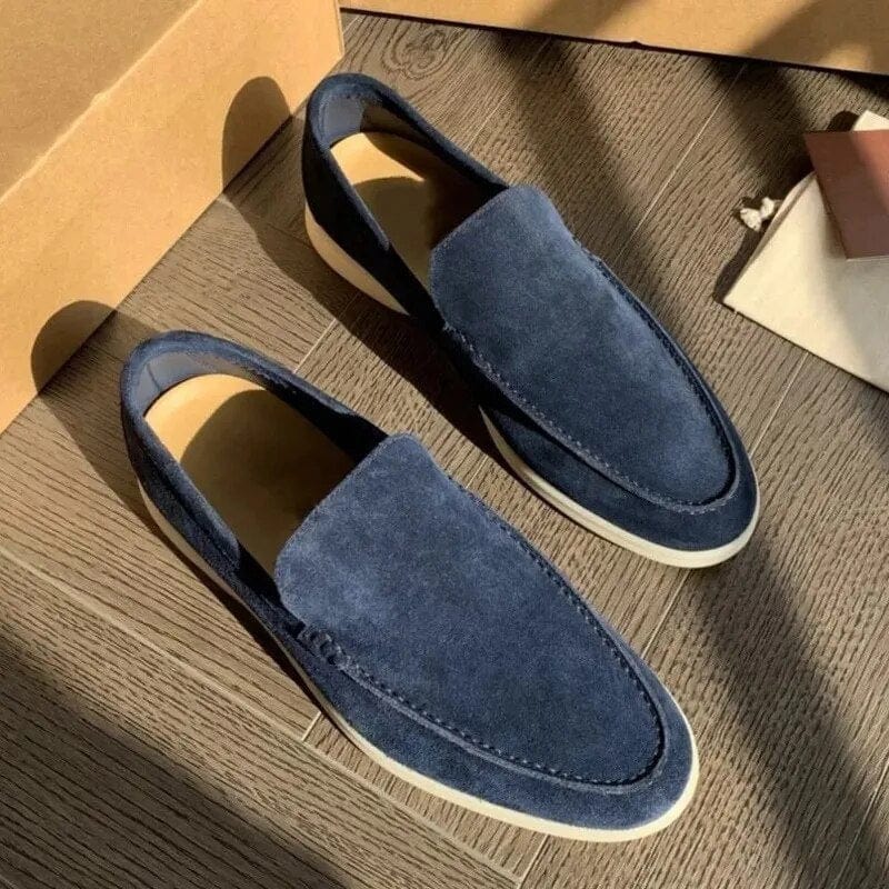 Mocassini uomo in camoscio blu, suola bianca, su pavimento in legno. Scarpe eleganti casual, moda maschile, calzature di tendenza.