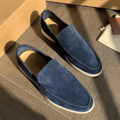 Mocassini uomo in camoscio blu, suola bianca, su pavimento in legno. Scarpe eleganti casual, moda maschile, calzature di tendenza.