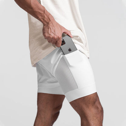Uomo in pantaloncini sportivi bianchi con tasca laterale, inserisce uno smartphone. Abbigliamento fitness, moda sportiva, tecnologia portatile.