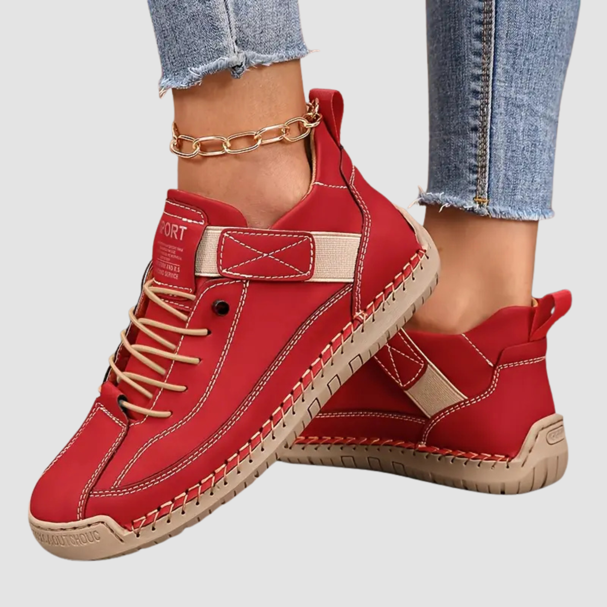 Scarpe sportive rosse da donna, design moderno con lacci beige e suola in gomma marrone, abbinate a jeans strappati e cavigliera dorata.