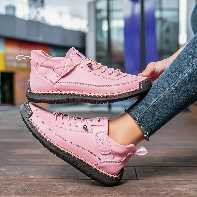 Scarpe da ginnastica rosa da donna con suola nera, indossate su pavimento in legno. Design moderno, casual e alla moda per passeggiate urbane.