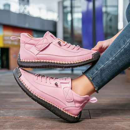 Scarpe da ginnastica rosa da donna con suola nera, indossate su pavimento in legno. Design moderno, casual e alla moda per passeggiate urbane.