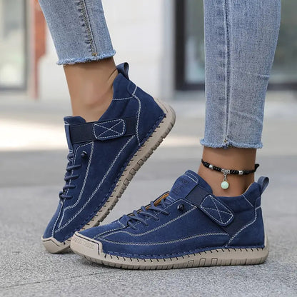 Scarpe da ginnastica blu in pelle scamosciata, indossate con jeans aderenti. Design casual, suola in gomma, perfette per moda urbana e comfort quotidiano.