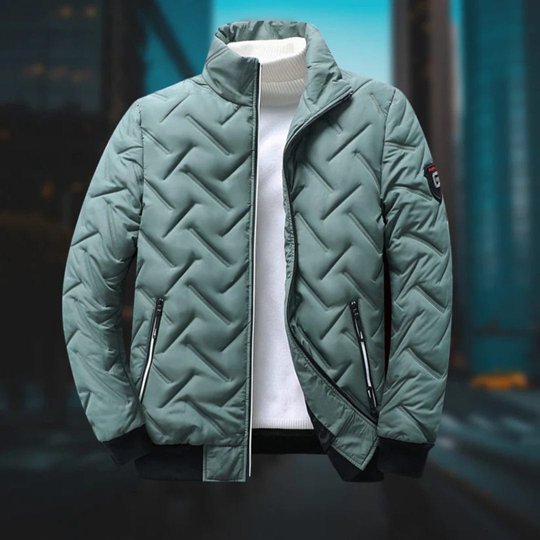 Giacca invernale trapuntata verde, con zip e colletto alto, su sfondo urbano sfocato. Design moderno, ideale per moda maschile autunno-inverno.