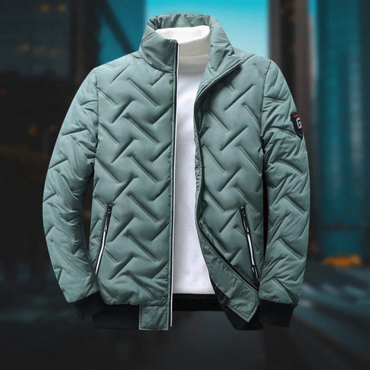 Giacca invernale trapuntata verde, con zip e colletto alto, su sfondo urbano sfocato. Design moderno, ideale per moda maschile autunno-inverno.