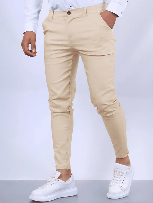 Pantaloni chino beige da uomo, vestibilità slim, abbinati a camicia bianca e sneakers bianche. Moda maschile elegante e casual.
