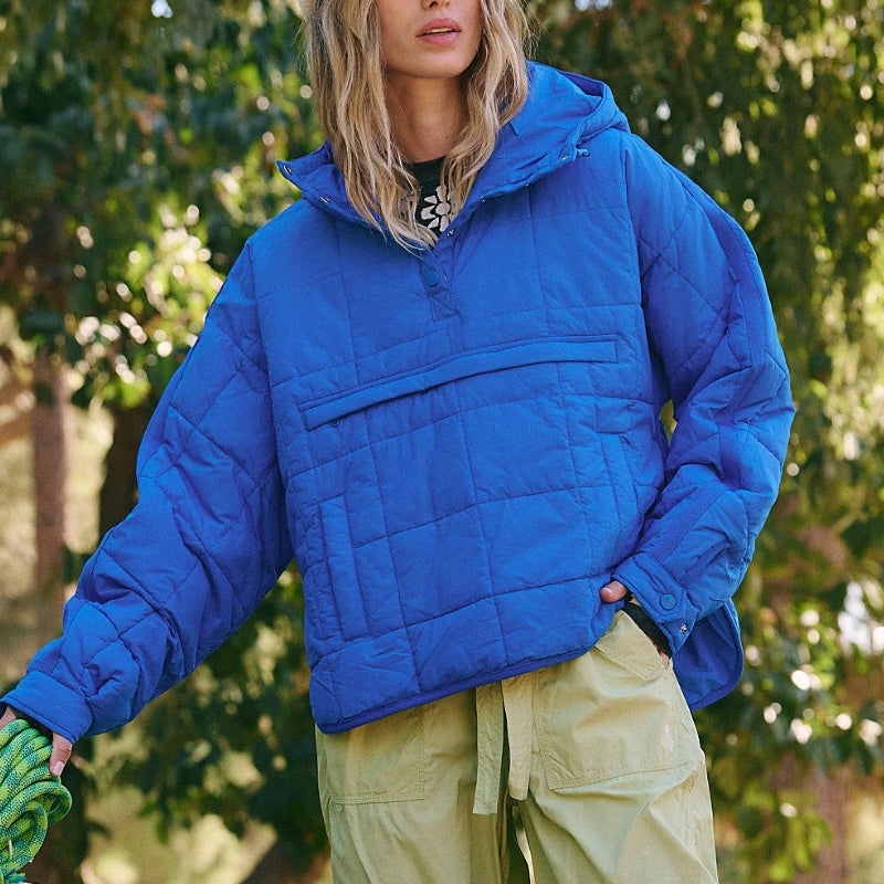 Giacca trapuntata blu brillante, indossata da una persona all'aperto, con pantaloni verde chiaro. Moda autunnale, abbigliamento casual.