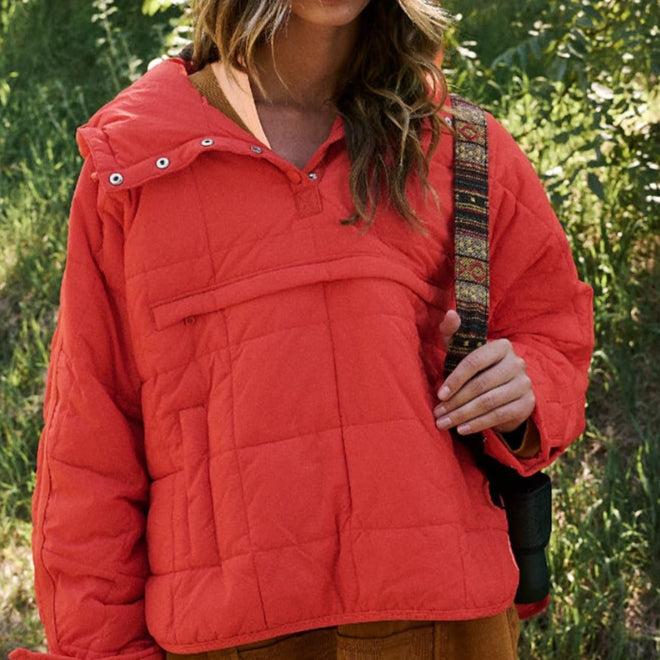 Giacca trapuntata arancione indossata da una donna in un ambiente naturale. Moda autunnale, abbigliamento casual, stile outdoor.