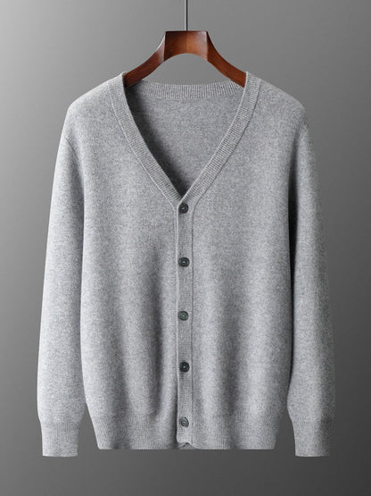 Cardigan grigio in lana, con scollo a V e cinque bottoni, appeso su gruccia di legno. Maglione elegante e caldo, ideale per moda autunnale.