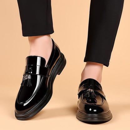 Scarpe mocassini uomo in pelle nera lucida con nappine, indossate con pantaloni eleganti neri. Calzature moda maschile, stile classico e raffinato.