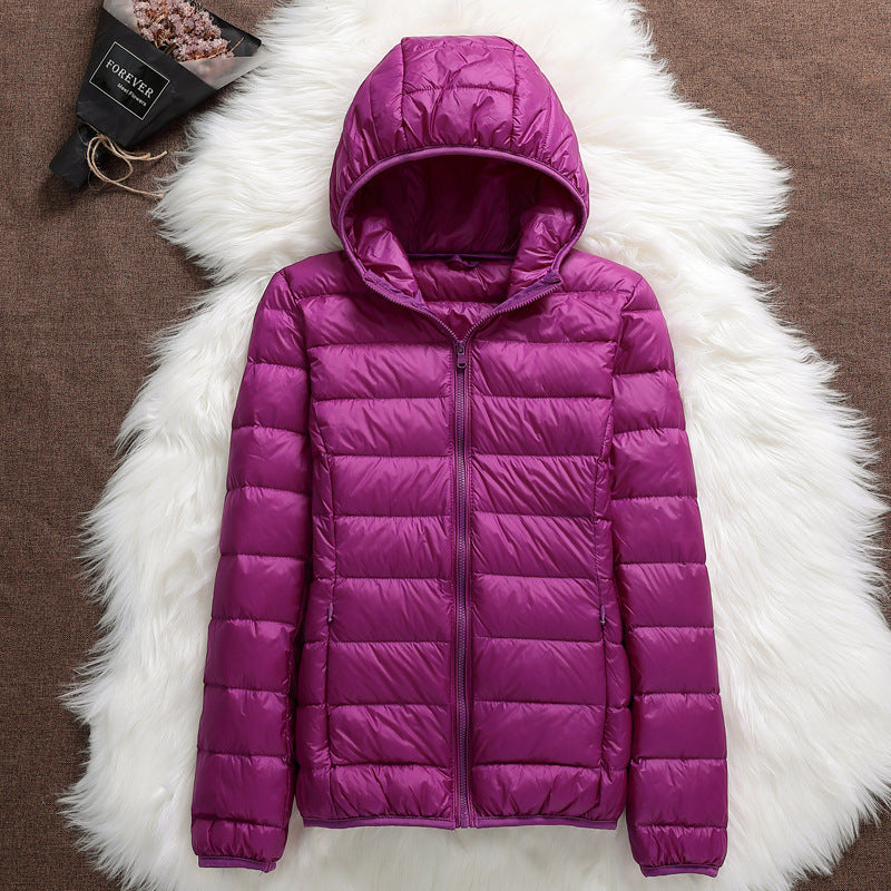 Giacca piumino viola con cappuccio su sfondo bianco peloso, moda invernale donna, abbigliamento caldo e leggero, stile casual ed elegante.