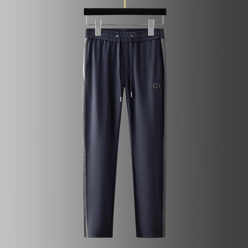Pantaloni sportivi grigi da uomo appesi, con logo, dettagli laterali a contrasto, elastico in vita e coulisse. Abbigliamento casual elegante.