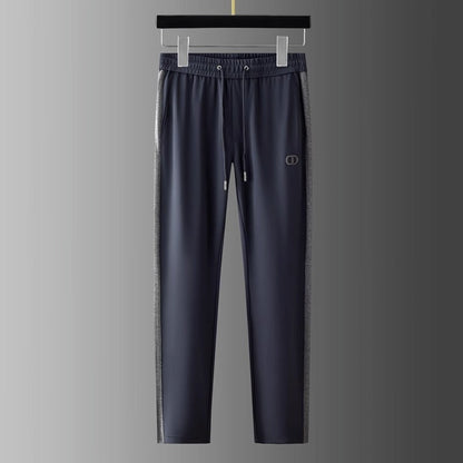 Pantaloni sportivi grigi da uomo appesi, con logo, dettagli laterali a contrasto, elastico in vita e coulisse. Abbigliamento casual elegante.