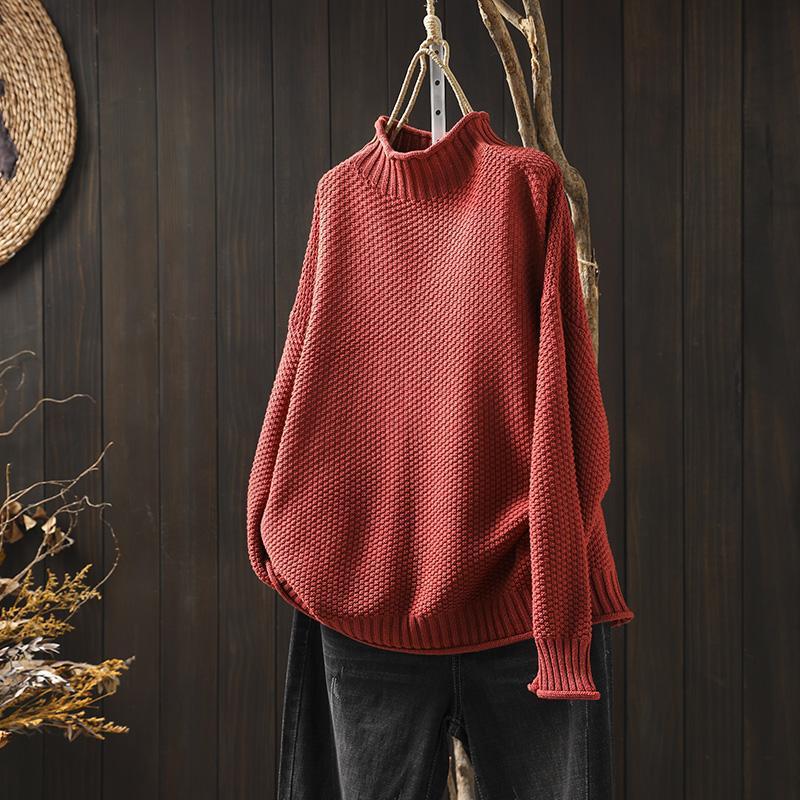 Maglione rosso a collo alto in maglia spessa, appeso su sfondo di legno scuro. Moda autunnale, abbigliamento caldo e accogliente.