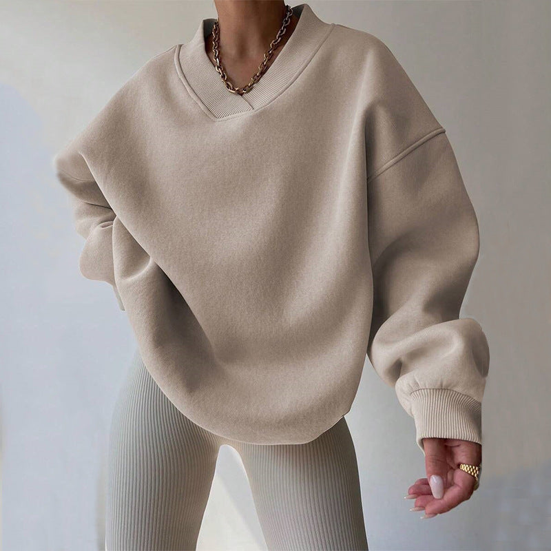 Donna con maglione oversize beige e collana dorata, indossa leggings a coste. Moda casual autunnale, stile minimalista, tendenze abbigliamento 2023.