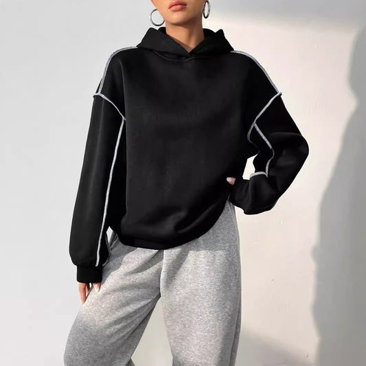 Donna con felpa nera oversize e pantaloni grigi, moda casual, abbigliamento sportivo, stile urbano, tendenze autunno inverno.