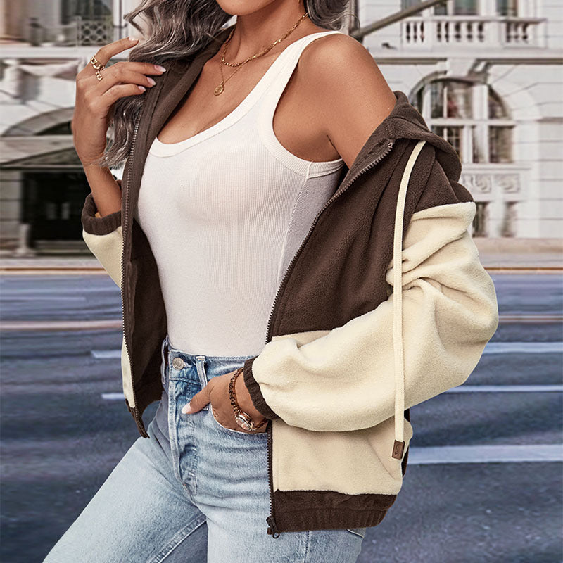 Donna con giacca bicolore marrone e beige, top bianco e jeans chiari. Moda urbana autunnale, abbigliamento casual femminile.