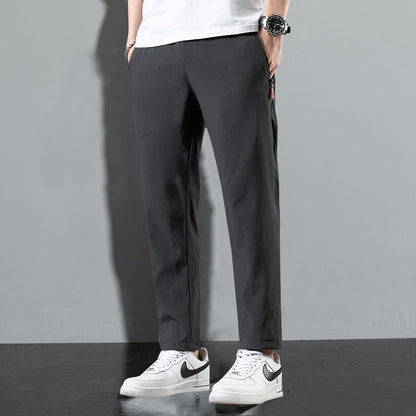 Pantaloni neri da uomo, stile casual, abbinati a scarpe da ginnastica bianche Nike, sfondo grigio. Moda maschile, abbigliamento urbano.