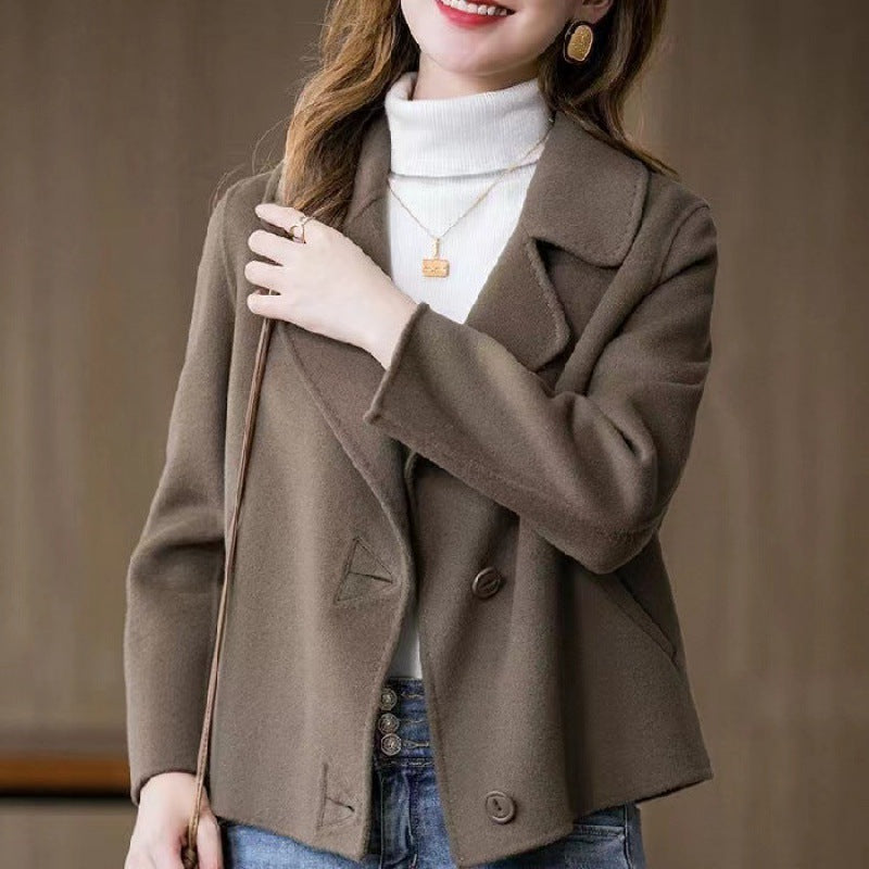 Donna con giacca marrone elegante, collo alto bianco, jeans, orecchini dorati e collana. Moda autunnale, abbigliamento casual chic.