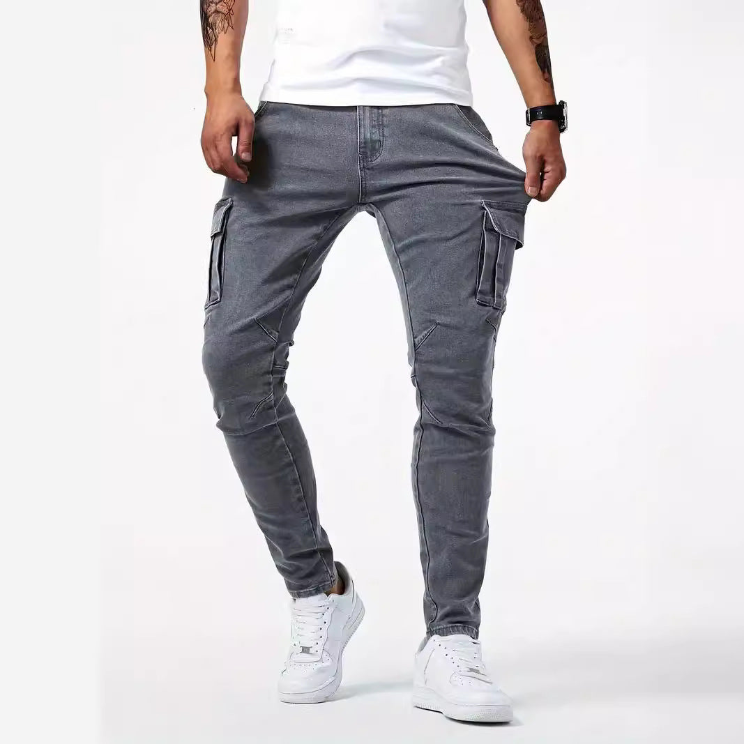 Jeans cargo grigi da uomo, vestibilità slim, tasche laterali, abbinati a scarpe da ginnastica bianche e maglietta bianca.
