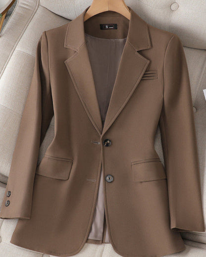Giacca elegante marrone da donna su appendiabiti, con due bottoni e tasche frontali, perfetta per abbigliamento formale e business casual.