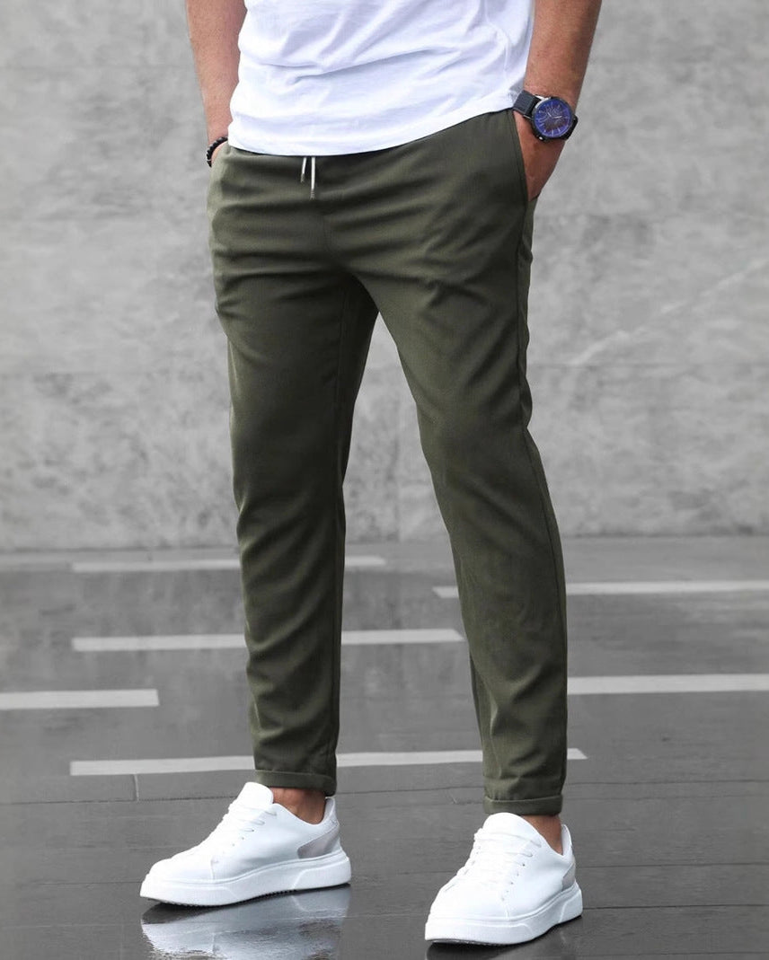 Uomo con pantaloni chino verde oliva, t-shirt bianca e sneakers bianche. Moda casual maschile, stile urbano, abbigliamento moderno.