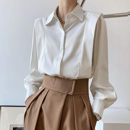 Camicia bianca elegante con colletto classico, abbinata a pantaloni marroni a vita alta. Look sofisticato e moderno per moda donna.