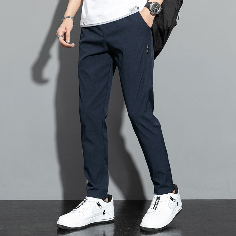 Pantaloni uomo blu scuro eleganti, abbinati a scarpe sportive bianche e maglietta bianca. Moda casual maschile, stile urbano moderno.