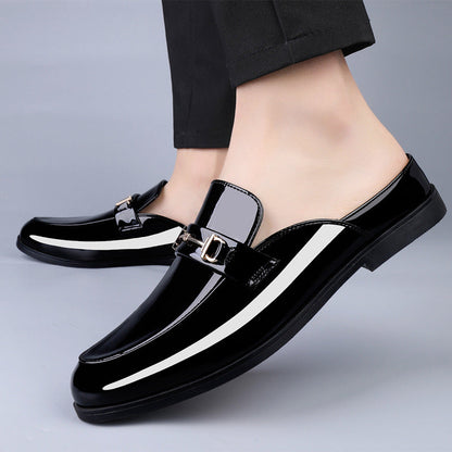 Scarpe mocassini uomo in pelle nera lucida, design elegante con fibbia metallica, indossate con pantaloni neri. Calzature moda maschile.