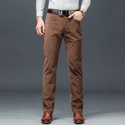 Uomo in camicia bianca e pantaloni marroni eleganti, cintura in pelle, scarpe in cuoio, posa su sfondo grigio. Moda maschile casual chic.