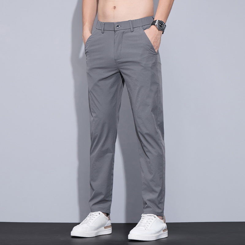 Pantaloni grigi da uomo eleganti, indossati con scarpe bianche e orologio, moda casual, abbigliamento maschile moderno.