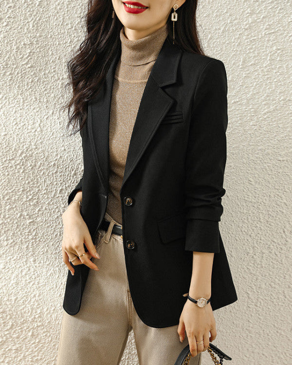 Donna con blazer nero elegante, dolcevita beige e pantaloni chiari. Moda autunnale, stile business casual, abbigliamento femminile sofisticato.