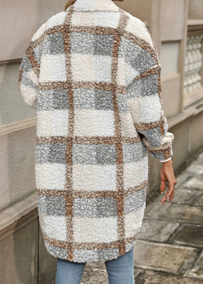 Cappotto in lana a quadri beige, grigi e bianchi, indossato da una persona di spalle su marciapiede urbano. Moda autunnale, stile casual chic.